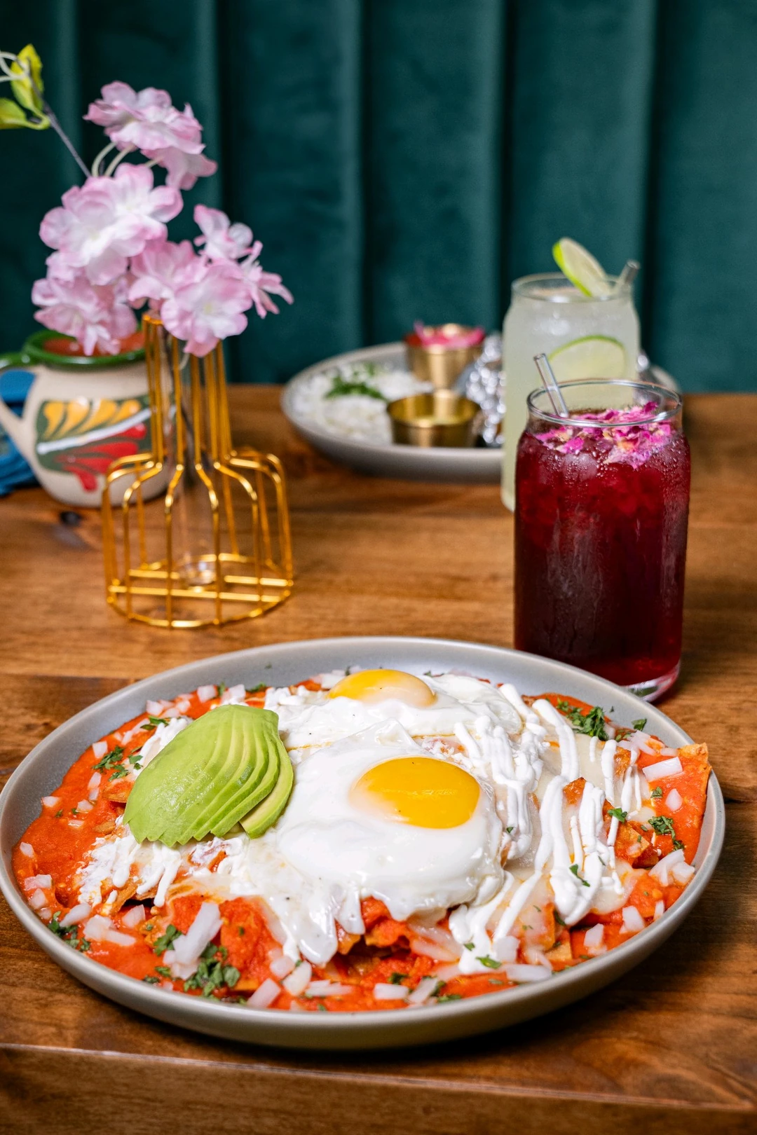 Chilaquiles, eggs and avocado beside drinks and flowers at Casa Jardín.