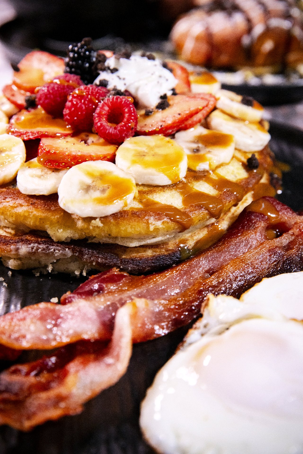Mousai’s fruit-topped brunch plate with bacon and eggs