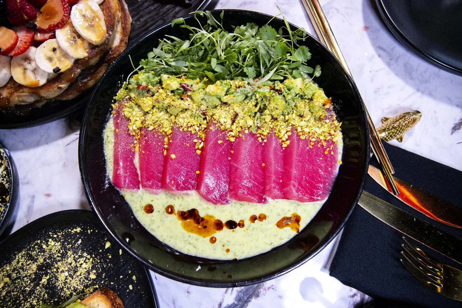 A tuna plate with green sauce and the surrounding dishes on Mousai’s real table