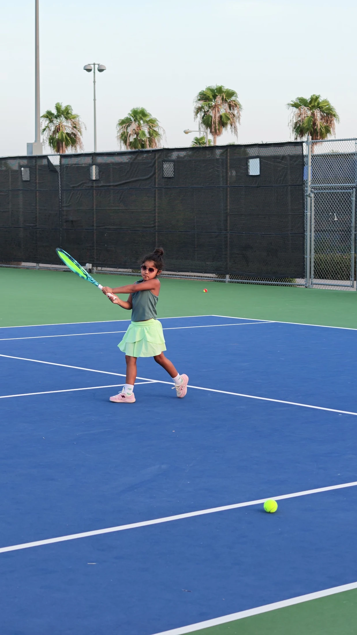 Penny practicing a backhand on a blue tennis court